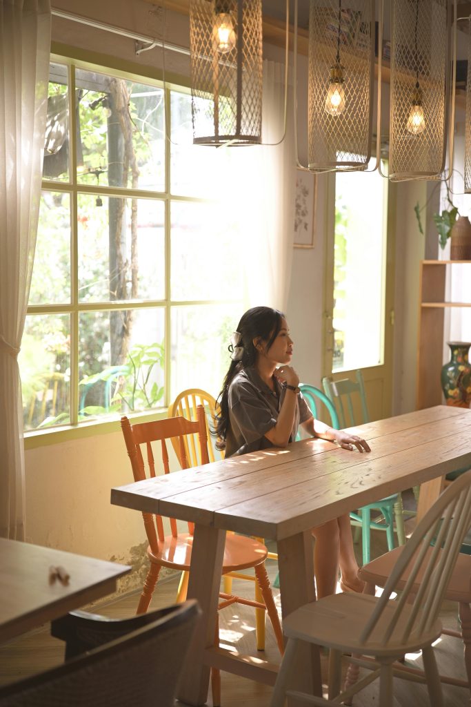Woman in a bright café enjoying sunlight through window.
