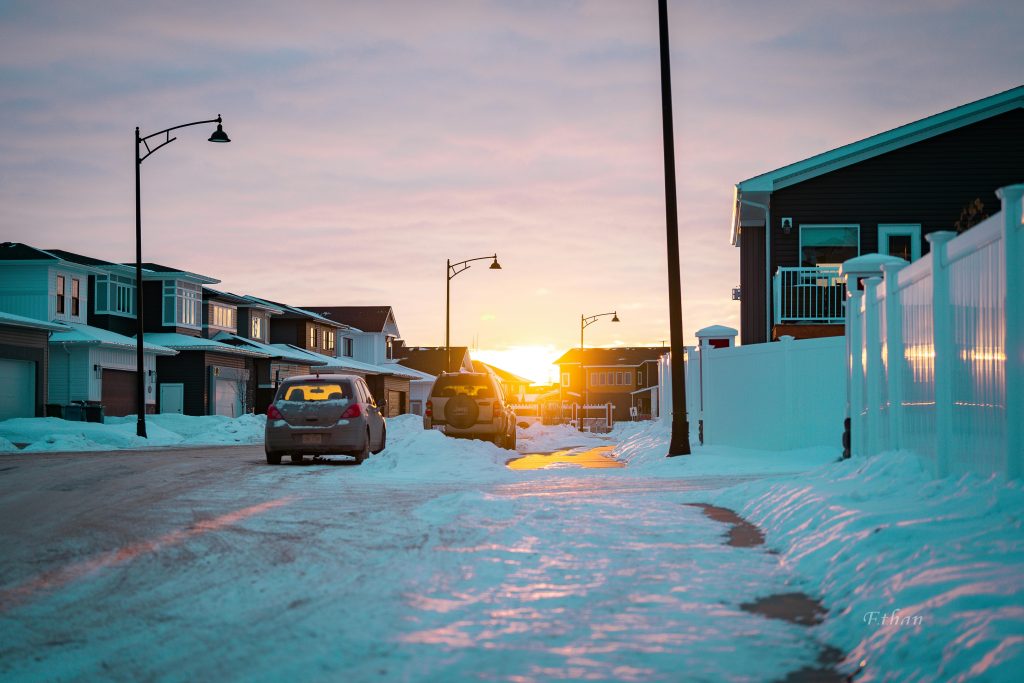 Beautiful winter sunset casting warm light over a snowy suburban street in Red Deer, Canada.