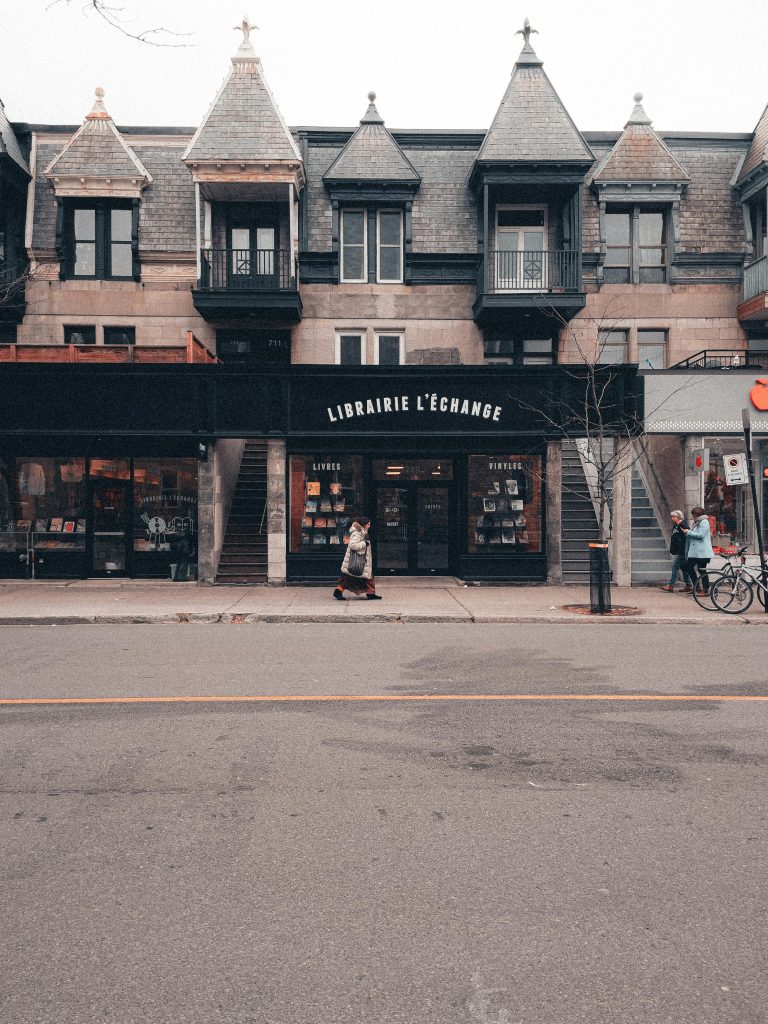 A charming street view of a bookstore facade with pedestrians passing by in an urban setting.