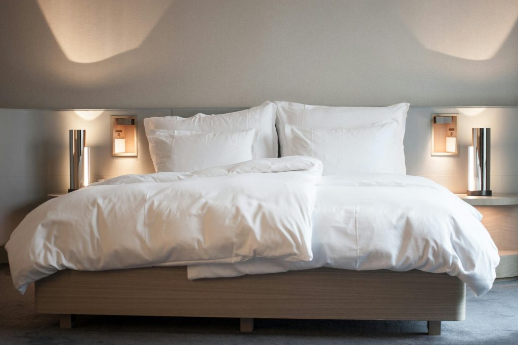 Elegant hotel room with comfortable bedding and modern lighting fixtures.