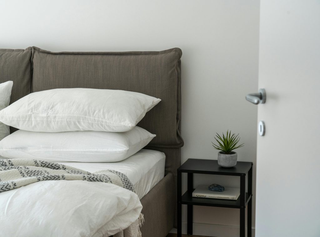 A serene and stylish bedroom featuring a comfortable bed with clean white bedding and a side table with decor.