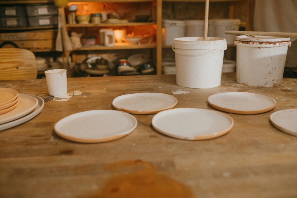 Artisan pottery plates drying in a rustic ceramic workshop with creative tools and materials.