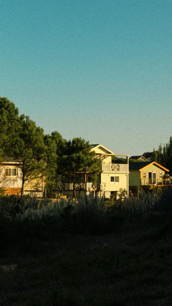 Sunset view of colorful houses surrounded by lush greenery in Punta del Diablo, Uruguay.