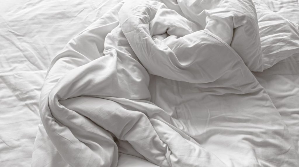 Crumpled white bedding inviting comfort and relaxation in a serene bedroom setting.