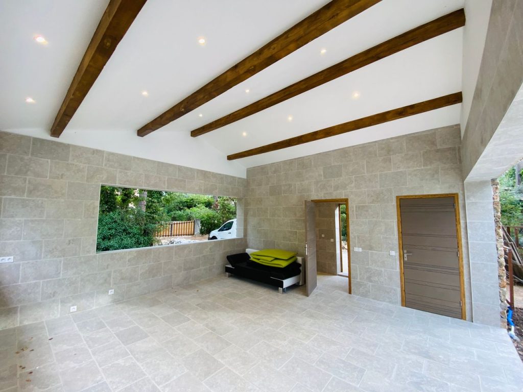 Spacious modern room with natural light, wooden beams, and stone walls.